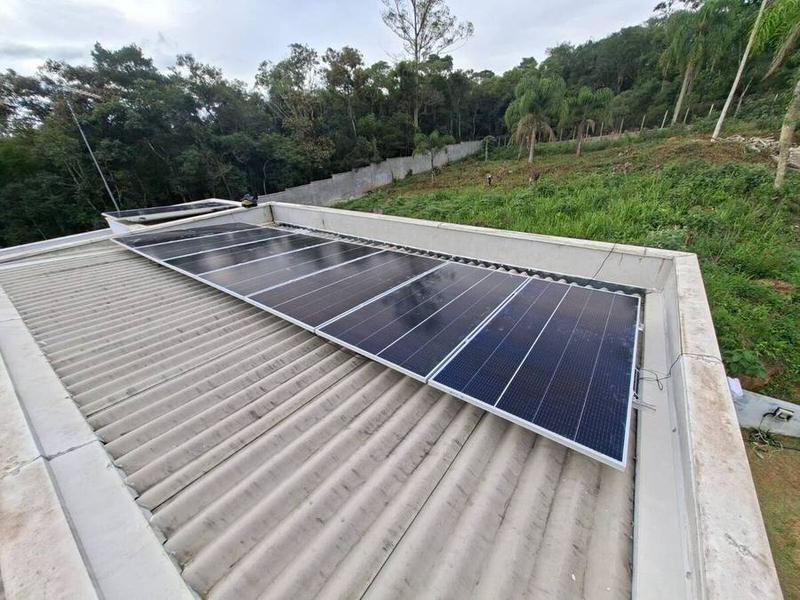 Painéis solares instalados em telhado com vista para floresta
