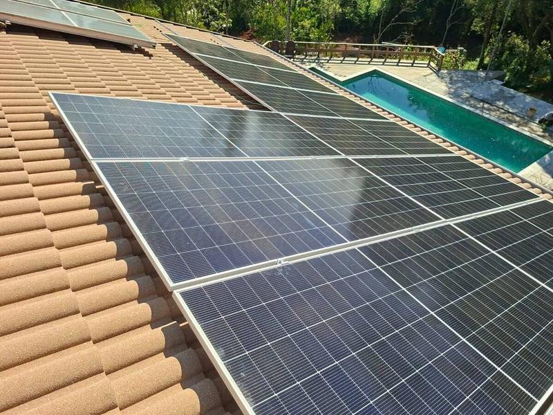 Painéis solares instalados em telhado com piscina ao fundo